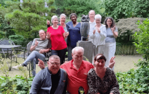 Groep huurders Ymere Amsterdam samen in groene tuin, lachend en genietend van de buitenlucht.