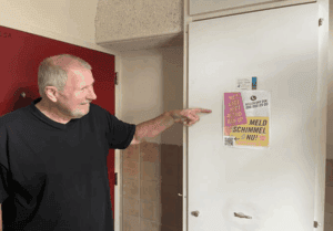 Man wijst naar poster over schimmelpreventie in huurwoning Ymere Amsterdam.