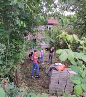 Huurders Ymere Amsterdam in een groene tuin, betrokken bij tuinonderhoud en sociale activiteiten.